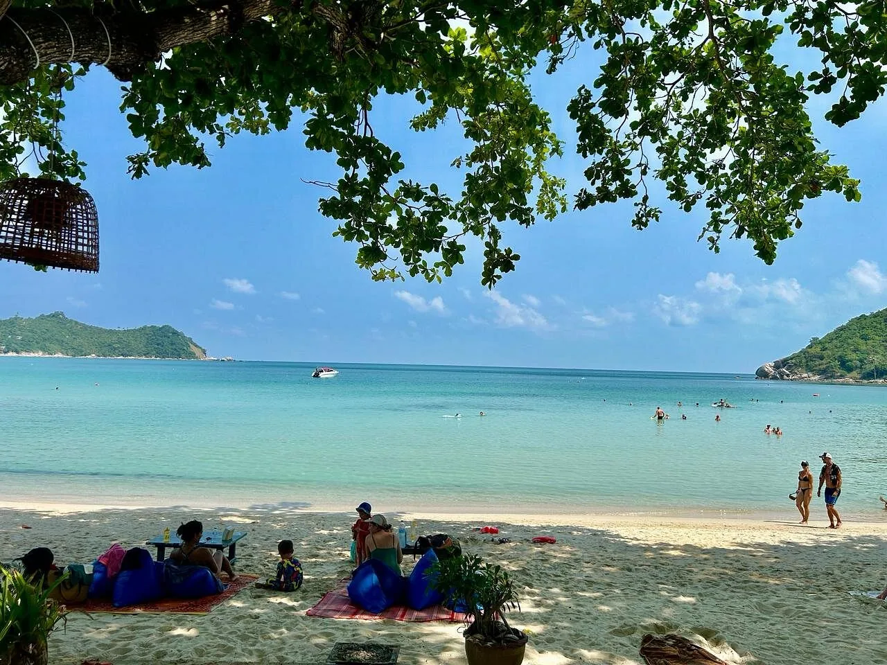 Thong Nai Pan Noi beach — shaded seating under trees, turquoise water
