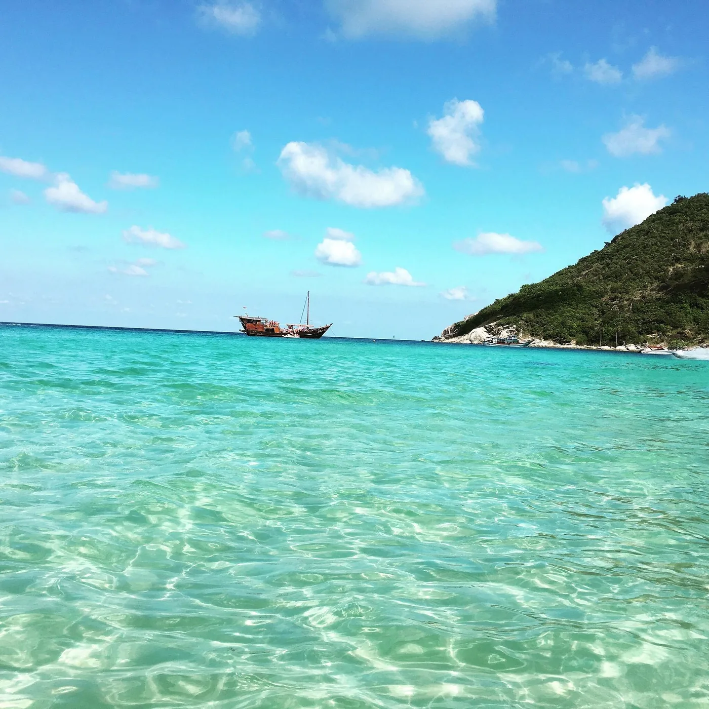 Crystal clear shallow water, wooden sailing ship on the horizon, Koh Phangan